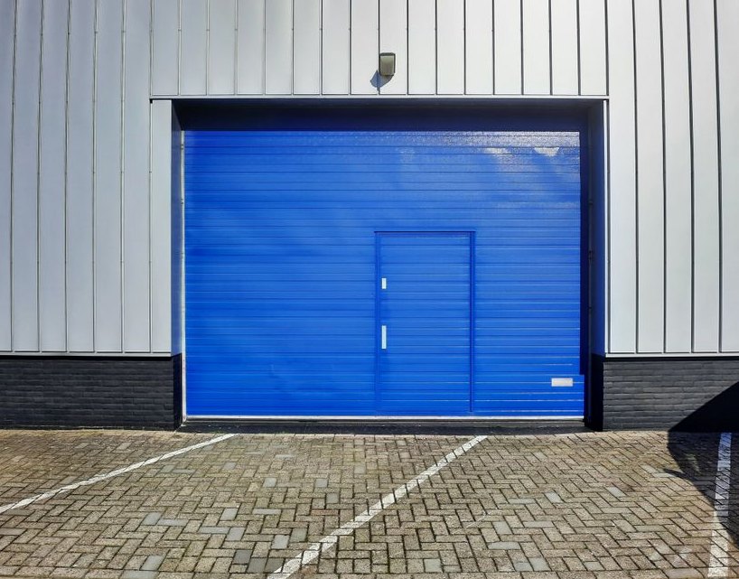 Wide shot of a modern industrial warehouse featuring a bright blue garage door