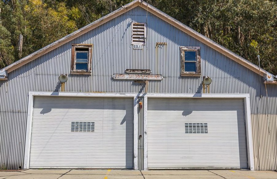 A sunlit vintage metal garage with double doors and rustic charm amidst trees